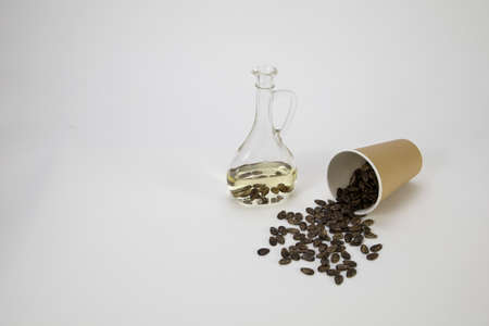 Watermelon seed oil in a bottle, watermelon seeds pour out of an eco glass on the tableの写真素材