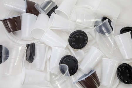Disposable plastic utensils scattered on the table, plastic utensils in a heap, mug, glasses, spoons and forksの写真素材