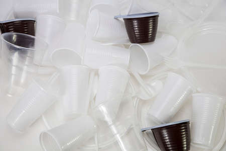 Disposable plastic utensils scattered on the table, plastic utensils in a heap, mug, glasses, spoons and forksの写真素材