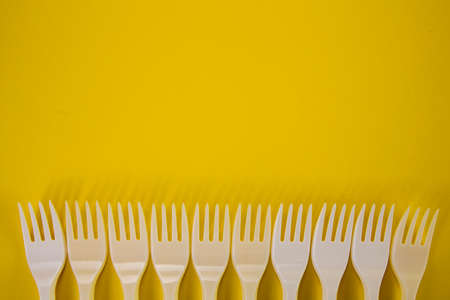 Plastic forks in one row on a yellowの写真素材