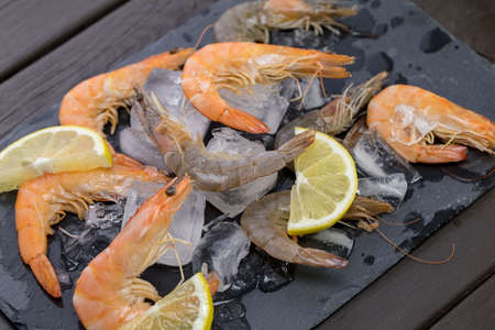 shrimp on a stone plate with ice, on the bg of a wooden tableの写真素材