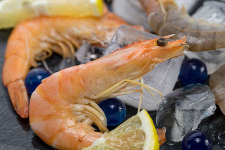 shrimp on a stone plate with ice, on the bg of a wooden tableの写真素材