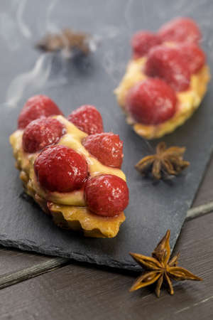 Raspberry cake with cream on a stone plate with aniseの写真素材