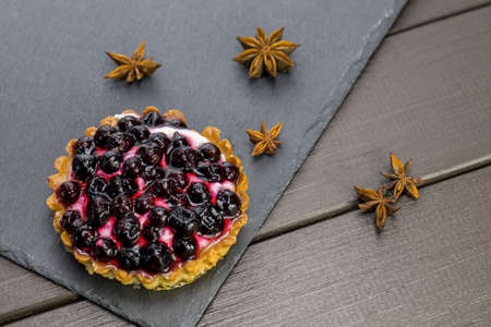 Cake with black currant and cream on a stone plate with aniseの写真素材