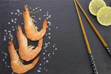 shrimp on a plate with lime and chopsticks on a black backgroundの写真素材