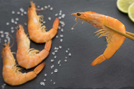 shrimp on a plate with lime and chopsticks on a black backgroundの写真素材