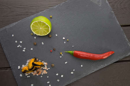 mussels on a stone plate with lime and red chili pepperの写真素材