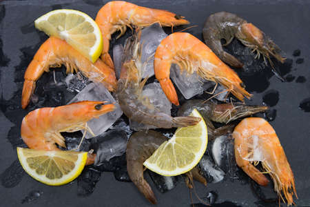 shrimp on a stone plate with ice, on the bg of a wooden tableの写真素材
