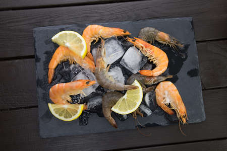 shrimp on a stone plate with ice, on the bg of a wooden tableの写真素材