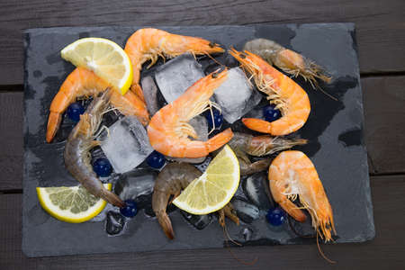 shrimp on a stone plate with ice, on the bg of a wooden tableの写真素材