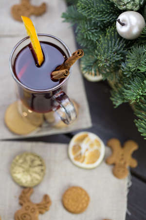 winter treats, a mug of warm wine with an orange, and cookies, ingredients on a wooden brown table. Traditional hot drink for Christmas, in the background Christmas composition.の写真素材