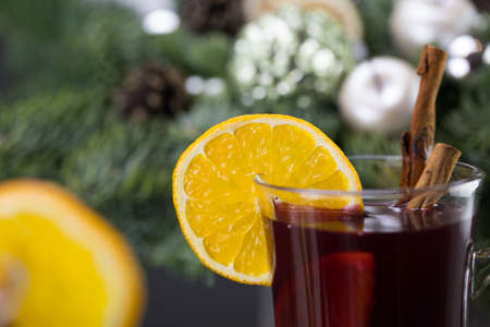 Mugs of warm wine with orange, cookies and cinnamon, dried fruit and spruce branches, Traditional hot drink for Christmas, close-up shot of warm wine.の写真素材