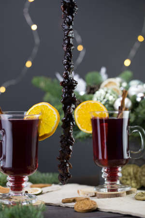 Mugs of warm wine with orange, cookies and cinnamon, dried fruit and spruce branches, Traditional hot drink for Christmas, close-up shot of warm wineの写真素材
