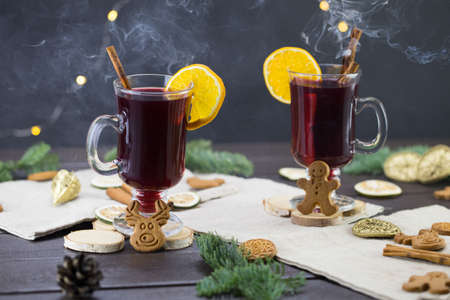 winter treats, a mugs of warm wine with an orange, and cookies, ingredients on a wooden brown table. Traditional hot drink for Christmas.の写真素材