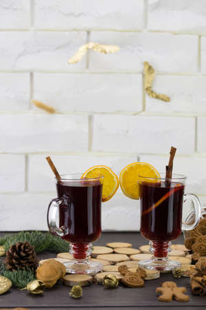 Mugs of warm wine with orange, cookies and cinnamon, dried fruit and spruce branches, hot drink for Christmas.の写真素材