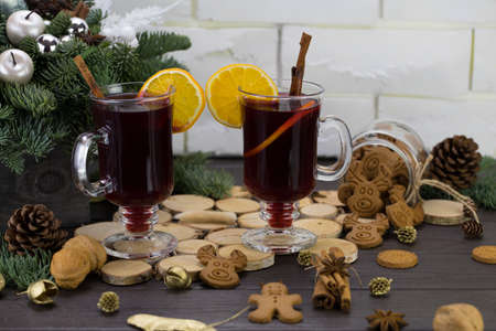 Mugs of warm wine with orange, cookies and cinnamon, dried fruit and spruce branches, hot drink for Christmas.の写真素材