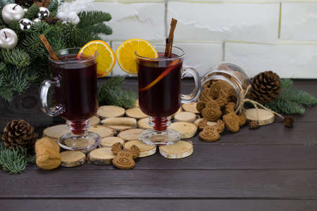 Mugs of warm wine with orange, cookies and cinnamon, dried fruit and spruce branches, hot drink for Christmas.の写真素材