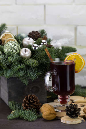 Mugs of warm wine with orange, cookies and cinnamon, hot drink for Christmas, on a wooden stand.の写真素材