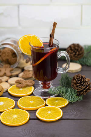Mugs of warm wine with an orange, a jar of cookies, next to cinnamon, a hot drink for Christmas, oranges on a wooden table.の写真素材