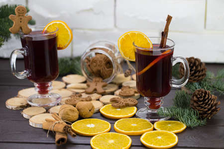 Mugs of warm wine with an orange, a jar of cookies, next to cinnamon, a hot drink for Christmas, oranges on a wooden table.の写真素材