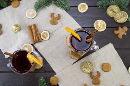 winter treats, a mugs of warm wine with an orange, and cookies, ingredients on a wooden brown table. Traditional hot drink for Christmas, in the background Christmas composition.の写真素材