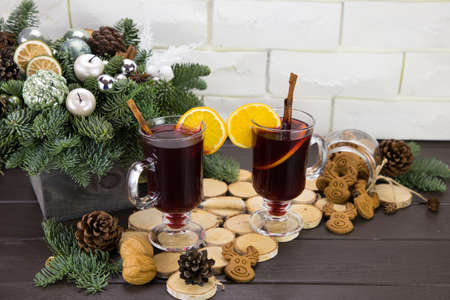 Mugs of warm wine with orange, cookies and cinnamon, dried fruit and spruce branches, hot drink for Christmas.の写真素材
