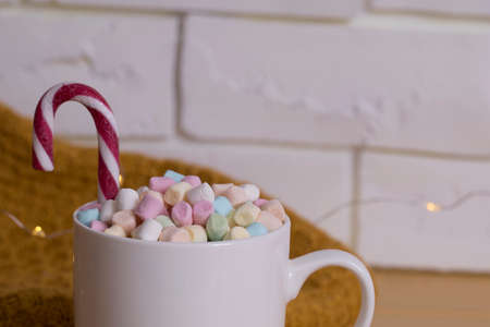 Mug with marshmallow, red and white christmas candy cane close-up.の写真素材