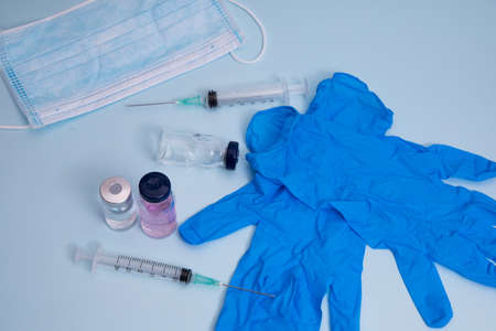 Medical bottle, vials, syringes and face mask on blue background with copy space. Vaccination session and immunity improvement.の写真素材