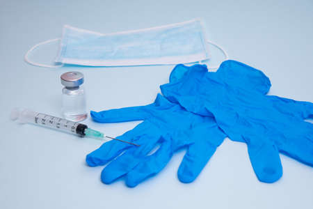 Medical bottle, vials, syringes and face mask on blue background with copy space. Vaccination session and immunity improvement.の写真素材
