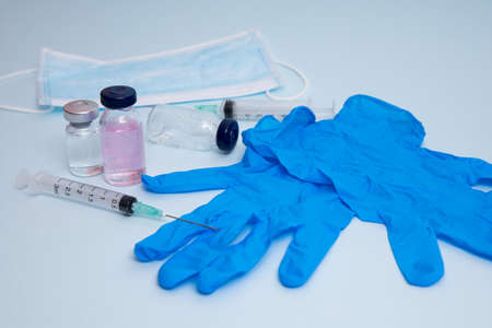 Medical bottle, vials, syringes and face mask on blue background with copy space. Vaccination session and immunity improvement.の写真素材
