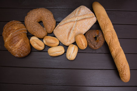 Bakery - gold rustic crusty loaves of bread and buns on black chalkboard background top view.