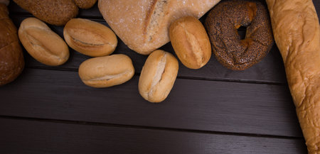Bakery - gold rustic crusty loaves of bread and buns on black chalkboard background top view.の写真素材