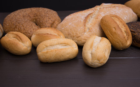 Bakery - gold rustic crusty loaves of bread and buns on black chalkboard background top view.の写真素材