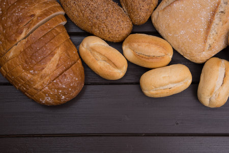 Bakery - gold rustic crusty loaves of bread and buns on black chalkboard background top view.の写真素材