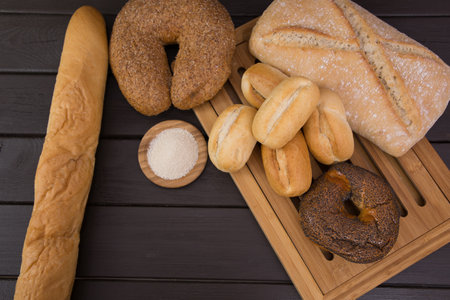 Bakery - gold rustic crusty loaves of bread and buns on black chalkboard background top view.の写真素材