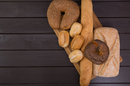 Bakery - gold rustic crusty loaves of bread and buns on black chalkboard background top view.の写真素材