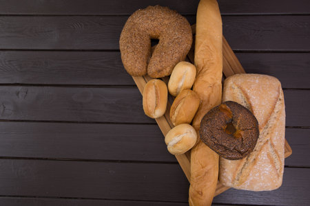 Bakery - gold rustic crusty loaves of bread and buns on black chalkboard background top view.の写真素材