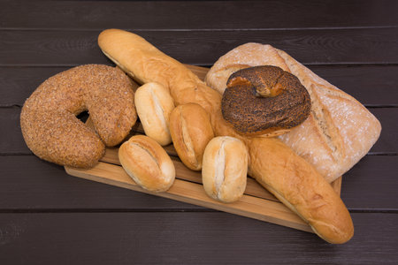 Bakery - gold rustic crusty loaves of bread and buns on black chalkboard background top view.の写真素材
