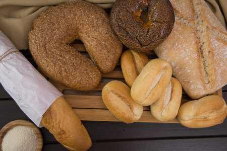 Bakery - gold rustic crusty loaves of bread and buns on black chalkboard background top view.の写真素材