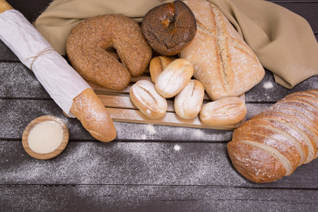 Bakery - gold rustic crusty loaves of bread and buns on black chalkboard background top view.の写真素材