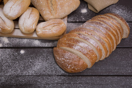 Bakery - gold rustic crusty loaves of bread and buns on black chalkboard background top view.の写真素材