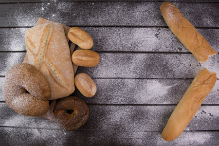 Bakery - gold rustic crusty loaves of bread and buns on black chalkboard background top viewの写真素材