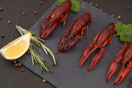 Delicious boiled crayfish close-up on a stone plate with lemon and parsley.の写真素材