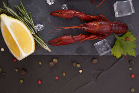 Delicious boiled crayfish close-up on a stone plate with pepper, lemon and parsley.の写真素材