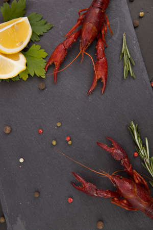 Delicious boiled crayfish close-up on a stone plate with pepper, lemon and parsley.の写真素材
