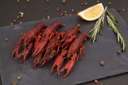 Delicious boiled crayfish close-up on a stone plate with pepper, lemon and parsley.の写真素材