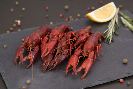 Delicious boiled crayfish close-up on a stone plate with pepper, lemon and parsley.の写真素材