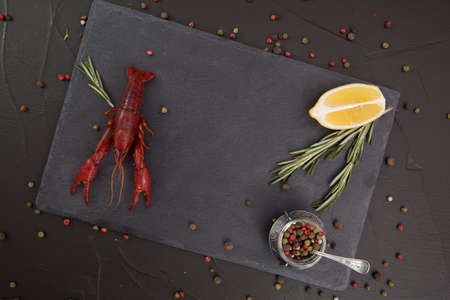Delicious boiled crayfish close-up on a stone plate with pepper, lemon and parsley.の写真素材