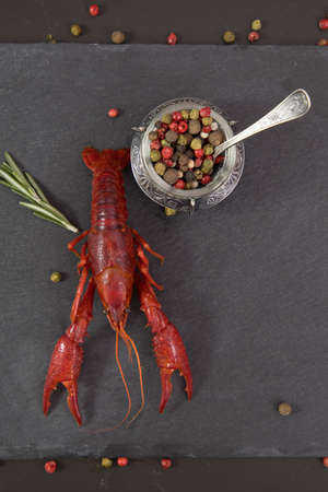 Delicious boiled crayfish close-up on a stone plate with pepper, lemon and parsley.の写真素材