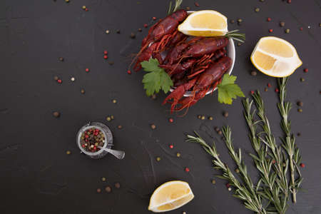 Delicious boiled crayfish close-up on a stone plate with pepper, lemon and parsley. free space for your text. Black background.の写真素材